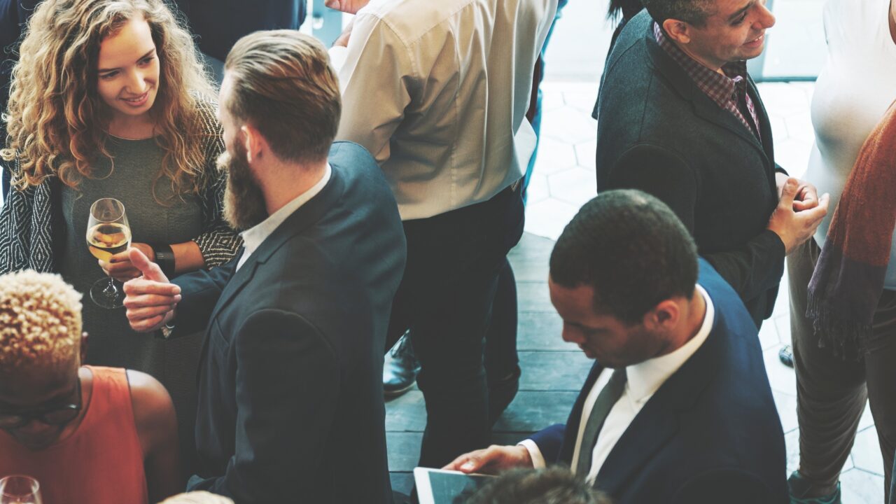 A group of people socializing at an association event and conversing with new members.