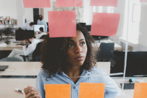 woman looking at sticky notes that would be replaced by membership software