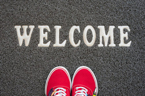 A pair of shoes on a welcome mat, representing a member welcome letter.