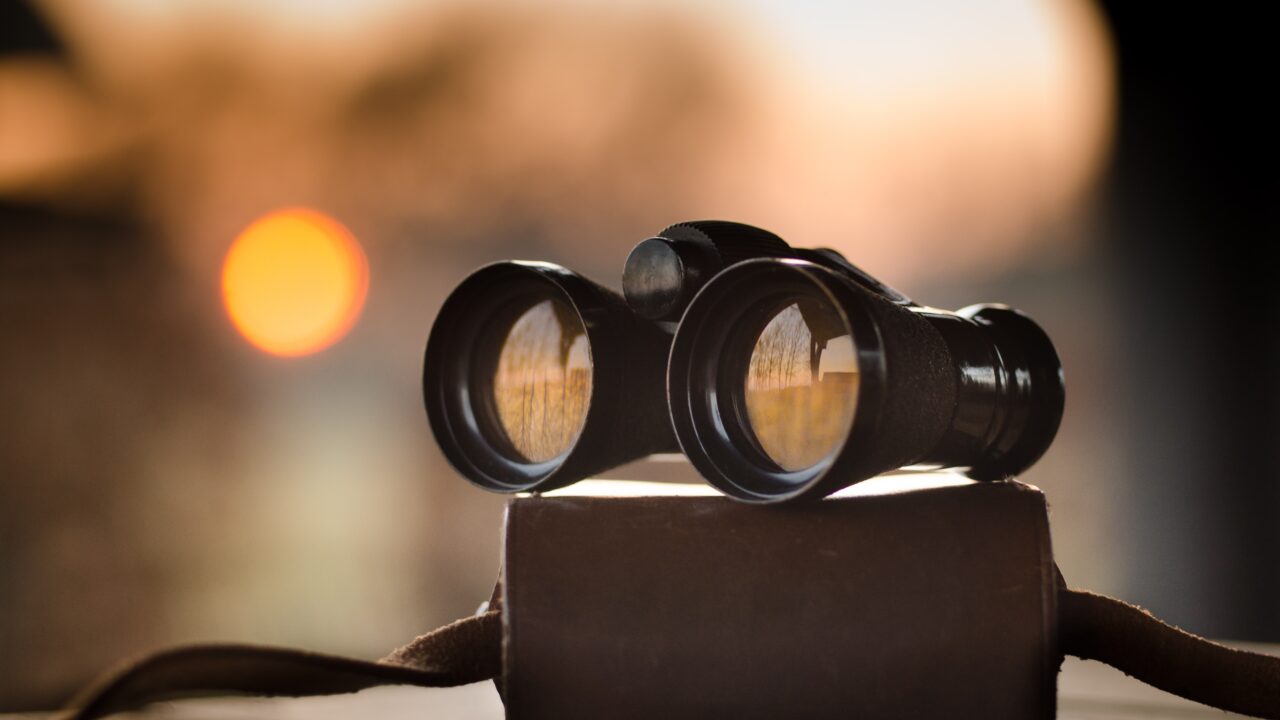 A pair of binoculars in front of a sunset background, reflecting how member directories can allow users to find what they are looking for.